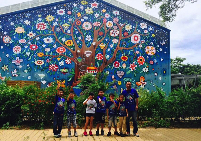 Three-story Mei Hua Gyro Tree of Life mural,  completed in March of 2015. Mei Hua (Beautiful Flower) Elementary School is located in a remote, rural area in Daxi, Taiwan. Most its students are from poor, indigenous, skip-generation and new immigrant families. In response to dwindling energy at the school, and a three-year drop in student population from 108 students to 43, the school invited Lily Yeh to lead a revitalization project through art.